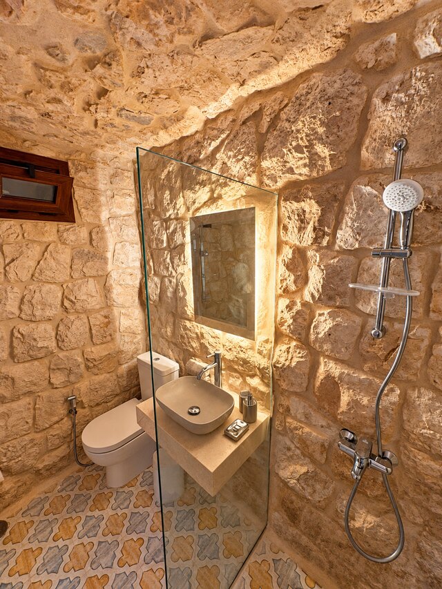 La Grande's walk-in shower, cut into the stone wall with a glass panel and a lit mirror.