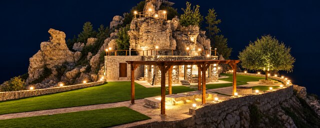 The terrace and pergola lit after dark beneath the ridge.