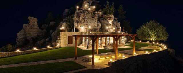 La terrasse et la pergola éclairées à la nuit tombée, sous la crête.